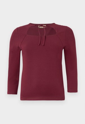Burgundy pitkähihaine toppi, jossa on pyöreä pääntie ja nauhakiinnitys. Etuolalla on leikkaus ja pehmeä, venyvä materiaali.