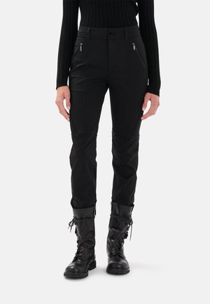Pantaloni neri aderenti realizzati in un materiale flessibile, dotati di tasche con zip, dettagli delle cuciture e progettati per un movimento dinamico.