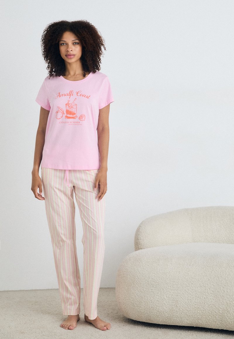 T-shirt de algodão rosa de manga curta com estampado "Costa Amalfitana"; calças de pijama risca, em rosa claro e creme, com cordão na cintura, em tecido suave.