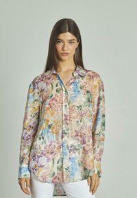 Camisa de manga larga floral en tejido ligero, con una mezcla de flores azules, rosas y amarillas, un collar estándar y cierre de botones en la parte delantera.