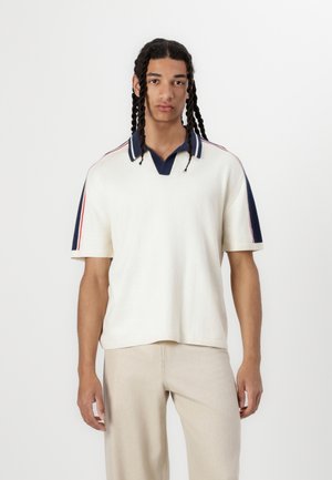 White short-sleeve polo shirt with a navy collar and red accent stripes on the sleeves. Made of textured fabric, relaxed fit.