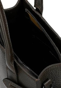 Brązowa skórzana torebka o fakturowanej powierzchni. Posiada otwarte górne wejście oraz zapinane na zamek przedziały, ukazujące ciemne wnętrze z jasnymi akcentami.