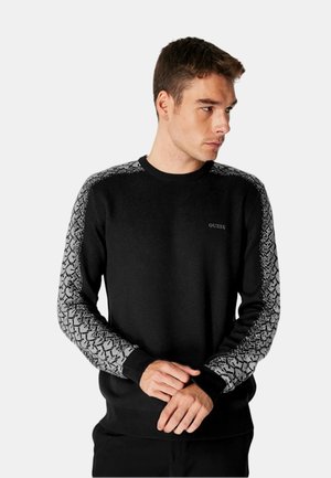 Maglione nero con accenti grigi a motivo sulle maniche, colletto girocollo, polsini e vita a coste. Presenta un logo discreto sul petto.