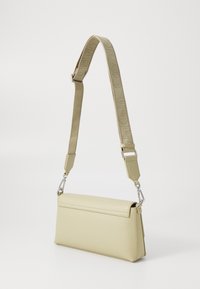 Bolso de hombro Calvin Klein en material texturizado de color verde claro con forma rectangular, que presenta una correa ancha y detalles en hardware plateado.