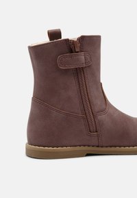 Bottines en simili cuir marron avec fermeture éclair latérale et languette, offrant une texture lisse, des coutures contrastantes et une semelle en caoutchouc.