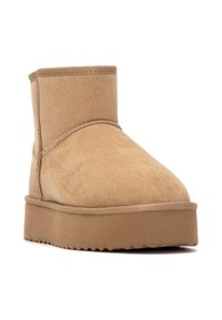 Botines en tono beige hechos de suave ante, con puntera redonda, detalles de costura y una suela de plataforma gruesa y texturizada.
