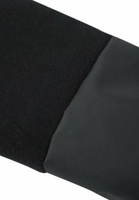 Un tissu tricoté noir se transforme en un matériau gris foncé lisse, présentant une surface texturée et un design épuré et angulaire.