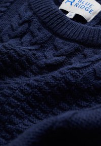Mörkblå kabelstickad tröja med ribbad krage och Blue Ridge-märke, storlek medium, närbild på den texturerade tyget.