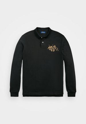 Musta pitkähihainen poolopaita, jossa on kaksi valkoista nappia ja vasemmassa rinnassa beige kirjailtu logo, jossa kaksi ratsastavaa poolopelaajaa.