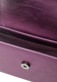 Lila läderväska med silvermagnetstängning, öppen för att visa den släta inredningen och detaljerad sömnad.