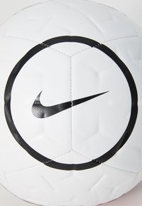 White soccer ball with hexagonal panels, black Nike logo and circular black graphic. Textured surface with stitching detail.
