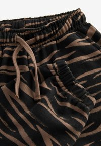 Sorte og brune mønstrede joggers med elastisk talje, snøre lukning og sidelommer, der fremviser et blødt, tekstureret stof.