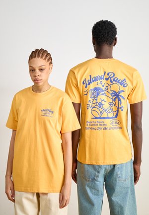 Gule bomulds t-shirts med tryk på front og bagside. Front har lille tekst, bagside har større grafik af et kamera og et palmetræ med musiknoter.