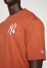 Oranje t-shirt met korte mouwen van katoen, met een wit 'NY' logo op de borst en een kleine witte accent op de mouw.