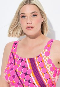 Badmode med rundad halsringning, med ett livfullt mönster i rosa och lila, slät textur och justerbara remmar för komfort.