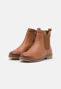 Botas de cuero marrón hasta el tobillo con paneles laterales elásticos, acabado suave, tacón bajo, detalles de costura y diseño de punta redondeada.