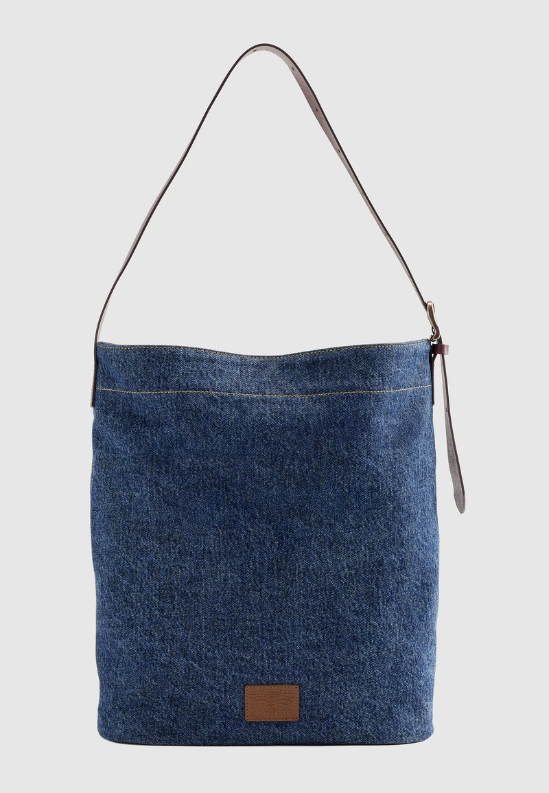 Blaue Jeans-Schultertasche mit einem verstellbaren einzelnen braunen Lederriemen und kleinem braunem Lederpatch auf der Vorderseite.