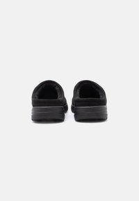 Melnas slip-on kurpes ar mīkstu zamšādas tekstūru, noapaļotu aizmuguri, mīkstinātu apkaklīti un gumijas zoli, kas izstrādātas komfortam un vieglai valkāšanai.
