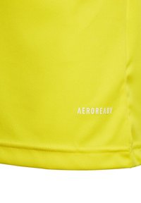 Tessuto sportivo giallo brillante con texture liscia, caratterizzato da un logo bianco "AEROREADY" vicino all'orlo, orlo cucito nella parte inferiore.