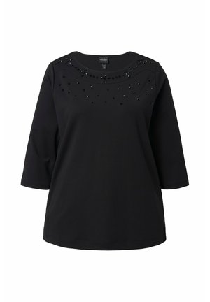 Haut noir à manches trois-quarts avec des perles décoratives autour du col, à la texture lisse et coupe ample.