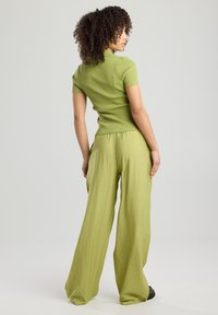 Lyhythihainen ribattu paita ja leveät housut teksturoidusta vaaleanvihreästä kankaasta, jossa on rento malli ja joustava vyötärö.