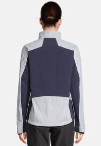 Veste colorée en bloc bleu marine et gris clair avec un col haut, des manches longues et une texture lisse, conçue pour le sport.