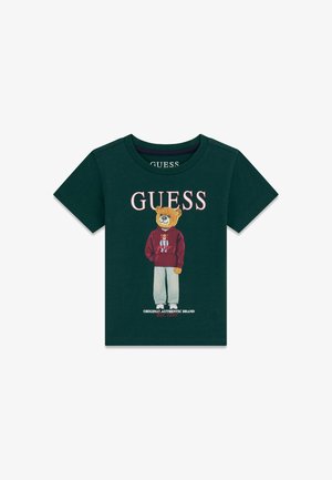 Tamnozelena majica kratkih rukava s ilustracijom medvjeda obučenog u hoodicu i hlače, a iznad je riječ "GUESS".