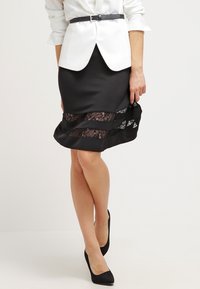 Mustat hameet, joissa on pitsi-inserttejä, muotoiltu malli, polvipituinen. Yhdistetty valkoisen paidan ja mustan vyön kanssa. Mustat korot täydentävät asua.