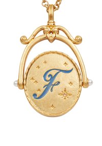 Zlatý náhrdelník s príveskom v tvare kruhového medailónu s modrým písmenným výrazom „F“, obklopený malými hviezdami a doplnený perlovými detailmi.