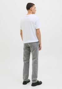 Valge puuvillane T-särk ümarate kaelustega, millele on lisatud hallid denim-joggid. Outfit täiendavad mustad kingad ja sellel on lihtne disain.