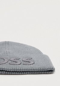 Sivé pletené čiapka s rebrovým vzorom a ohnutým vulkom. Na prednej strane má vyšívané písmená. Vyrobená z mäkkého, elastického materiálu.