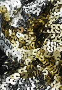 Metalni šljokici u srebrnoj i zlatnoj boji, blizu poredani, prikazujući različite nijanse sjaja i okrugli oblik s malim rupicama za šivanje.