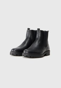 Botas de cuero negro hasta el tobillo con punta redonda, paneles laterales elásticos y suelas de goma gruesa con un diseño de relieve para mayor agarre.