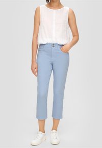 Pantalones cortos de color azul claro, confeccionados en una mezcla de algodón, con cierre de botón frontal y bolsillos laterales, combinados con una blusa blanca de lino suelta.
