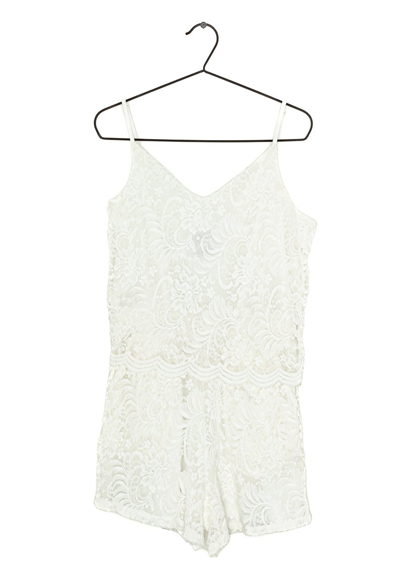 Romper en dentelle blanche avec des bretelles spaghetti, présentant un décolleté en V et de délicats motifs floraux tout au long. Suspendu à un crochet en métal noir.