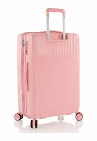 Harte rosa Koffer mit strukturierter Oberfläche, vertikalen Rillen, ausziehbarem Griff und vier multidirektionalen Rollen für eine einfache Mobilität.