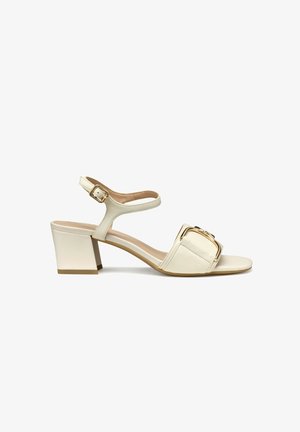 Sandalias de tacón cuadrado en cuero crema con una amplia tira de dedo cuadrada que presenta un detalle en hebilla dorada. Tira para el tobillo con hebilla ajustable.