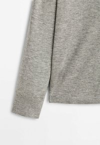Pull gris avec un tricot texturé, présentant un ourlet arrondi et des poignets côtelés. Le tissu est doux et léger, idéal pour le superposition.