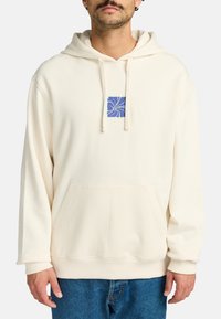 Hoodie de couleur crème avec une poche avant à rabat, capuche à cordon de serrage et graphique floral bleu sur la poitrine. Tissu doux avec une coupe décontractée.