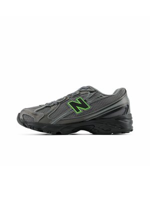 Chaussure de sport grise avec semelle noire et logo vert "N" sur le côté, avec superpositions en mesh et synthétiques et fermeture à lacets.