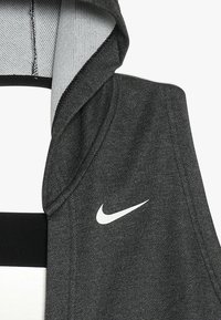 Harmaa urheiluhuppari, jossa pehmeä ja teksturoitu kangas; siinä on huppu ja valkoinen Nike-logo edessä. Alareunassa musta korostus.
