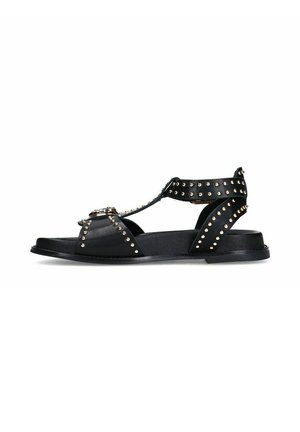 Sandales en cuir noir avec des accents cloutés, design à bout ouvert et talon découvert, semelle plate et bride cheville ajustable. Quincaillerie en métal doré remarquable.