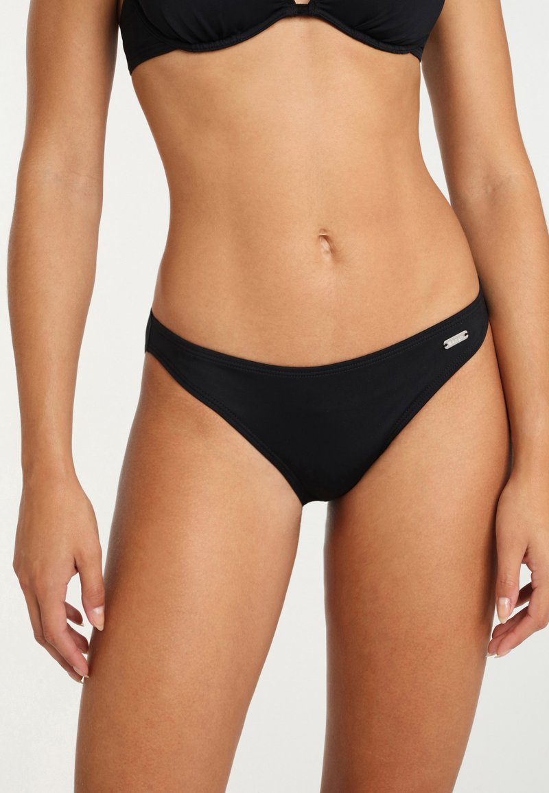 Juodas bikini apatinis kostiumėlis, pagamintas iš lygaus audinio, su žemu kirpimu, minimalia dengimo zona ir mažu sidabriniu logotipo akcentu šone.