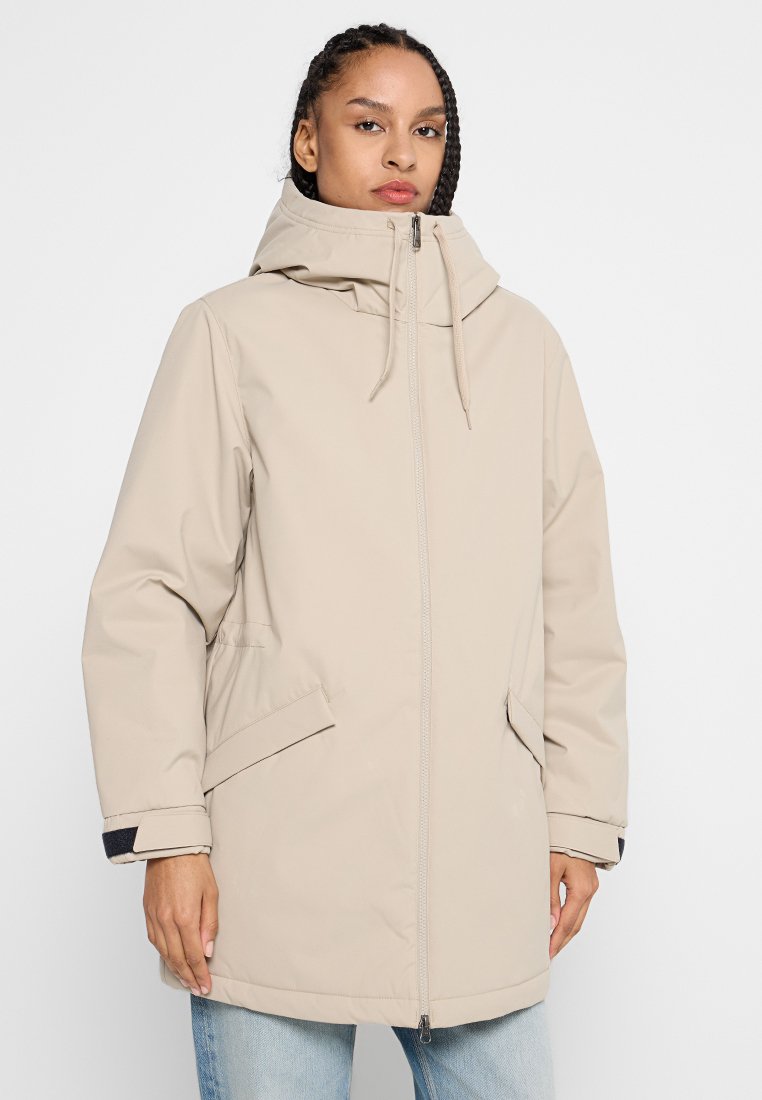 Beige waterdichte parka jas met een capuchon, ritssluiting aan de voorkant en zijzakken. Voorzien van een verstelbaar trekkoord in de capuchon en de manchetten.