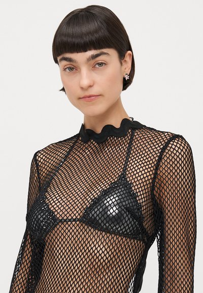 Haut à manches longues en mesh noir avec un décolleté festonné, superposé sur un bralette triangulaire noir brillant, avec un motif de tissage ouvert.