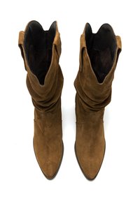 Botas de ante marrón hasta el tobillo con un diseño arrugado, puntera puntiaguda y detalle de borde en forma de ondas. Forro interior negro suave.