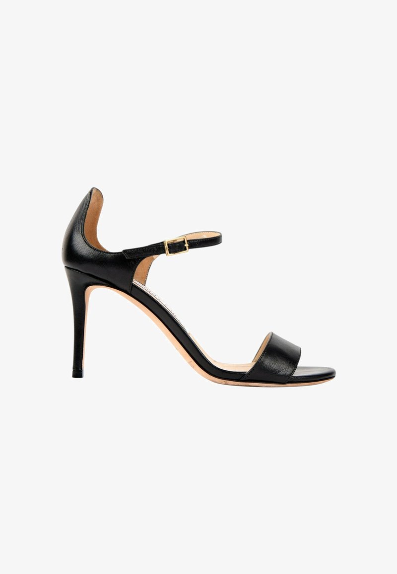 Sandale noire en cuir à talon haut avec bride cheville et boucle dorée, bout ouvert et talon fin sur fond blanc.
