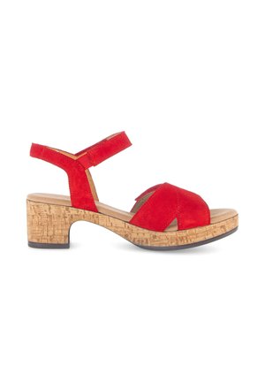 Rode suède sandaal met verstelbare enkelriem, open teen en lage kurken blokhak op witte achtergrond.