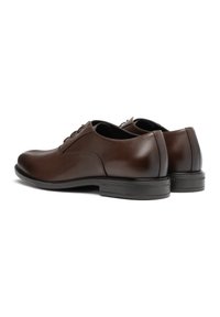 Scarpe da dress in pelle marrone con finitura liscia, punte arrotondate e lacci. Presentano un tacco basso e suole in gomma piatte.