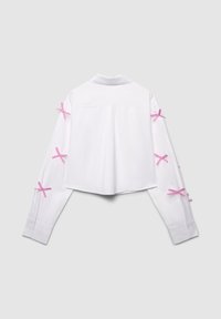 Weißes, kurz geschnittenes Hemd mit langen Ärmeln und pinkfarbenen Bandakzenten, die um die Oberarme gebunden sind, sowie einem klassischen Kragen.